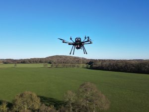 ISS Aerospace Sensus M drone in flight in a blue sky over green landscape
