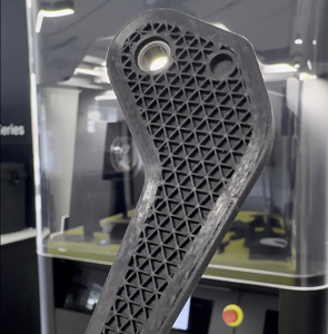 continuous carbon fibre reinforced part in front of the Markforged FX10 3D printer